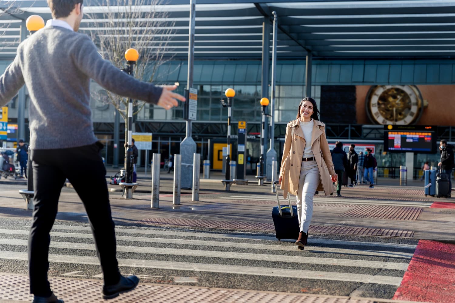 Mujer llegando al aeropuerto con maleta en un viaje navideño mientras un familiar la recibe a la salida.
